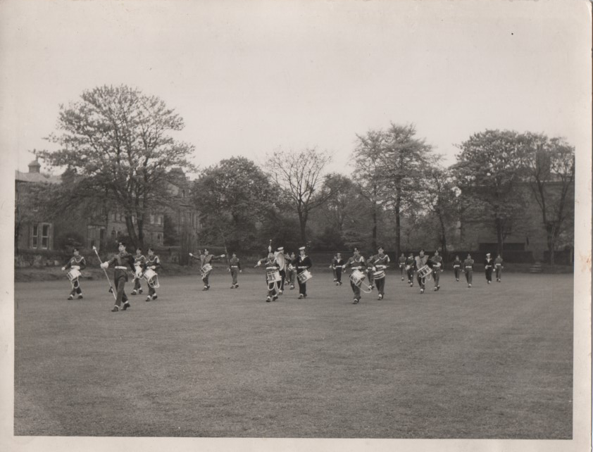 The Birkenhead School Combined Cadet Force band marching on the school playing field