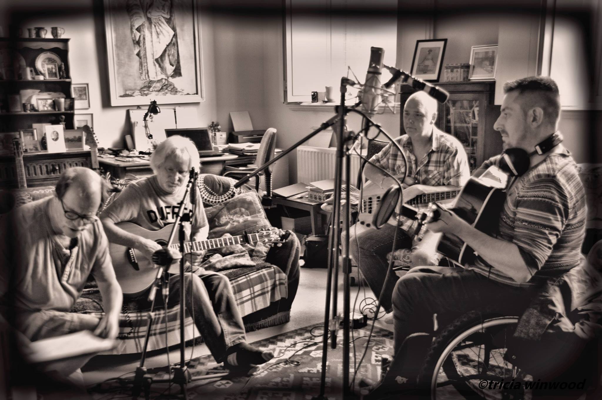 The Ol' Faithful recording in a living room, three guitarists and a bass player around two microphones, sepia
