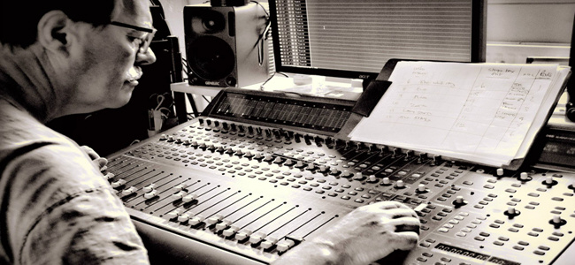 Pete at a mixing desk in the studio with a track sheet propped in front of him